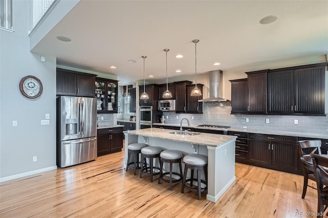 23503 E Minnow Dr, Aurora, CO 80016 - kitchen with appliances with stainless steel finishes, wall chimney range hood, backsplash, light wood-style flooring, and recessed lighting