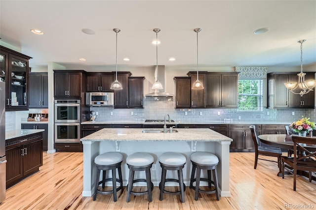 23503 E Minnow Dr, Aurora, CO 80016 - kitchen featuring wall chimney exhaust hood, appliances with stainless steel finishes, light wood-style floors, and decorative backsplash
