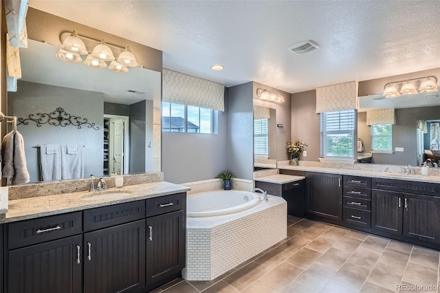 23503 E Minnow Dr, Aurora, CO 80016 - bathroom with healthy amount of natural light, a bath, two vanities, and a textured ceiling