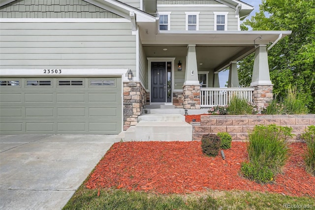 23503 E Minnow Dr, Aurora, CO 80016 - view of front facade with covered porch, stone siding, concrete driveway, and a garage