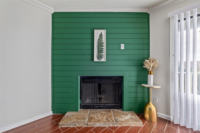 interior details featuring wood-type flooring, crown molding, and a tiled fireplace