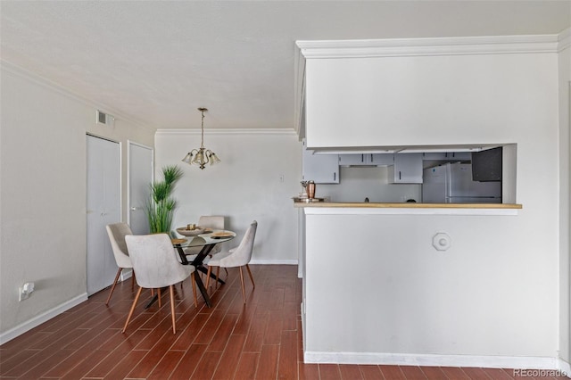 dining space featuring wood-type flooring, ornamental molding, and a notable chandelier