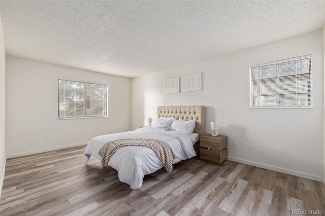 bedroom with a textured ceiling and light hardwood / wood-style floors