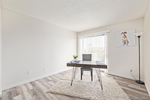 home office with light hardwood / wood-style flooring and a textured ceiling