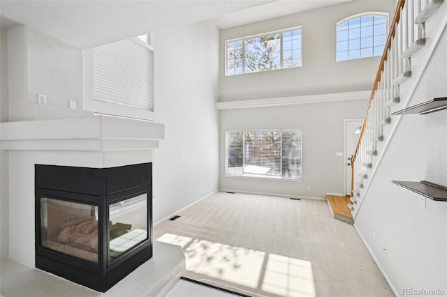 1272 Braewood Ave, Highlands Ranch, CO 80129 - unfurnished living room with stairway, a multi sided fireplace, a high ceiling, carpet, and baseboards
