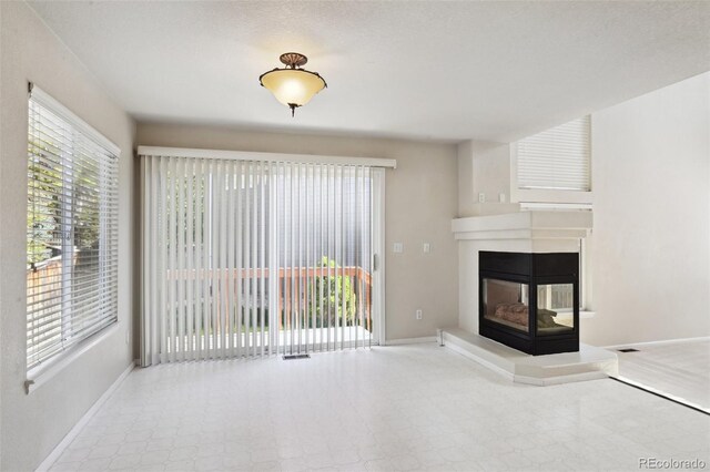 1272 Braewood Ave, Highlands Ranch, CO 80129 - unfurnished living room featuring plenty of natural light, baseboards, and a multi sided fireplace
