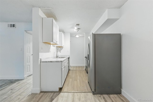 7755 E Quincy Ave Unit 107D2, Denver, CO 80237 - kitchen featuring appliances with stainless steel finishes, a sink, light countertops, light wood-type flooring, and a textured ceiling