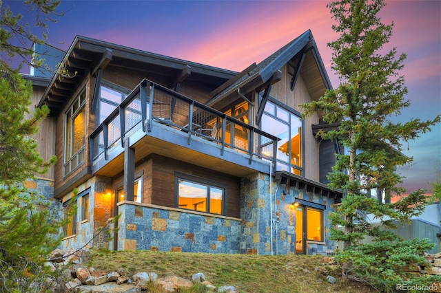 back house at dusk featuring a balcony