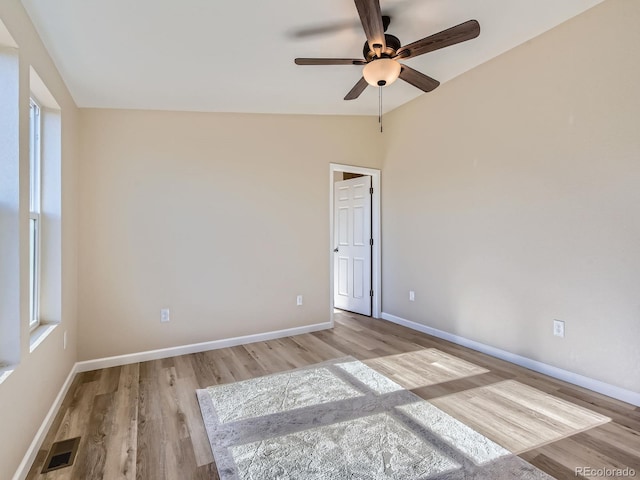 empty room with lofted ceiling, ceiling fan, and light hardwood / wood-style flooring