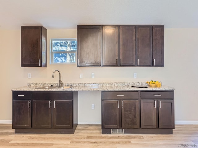 kitchen with dark brown cabinetry, light hardwood / wood-style floors, and sink