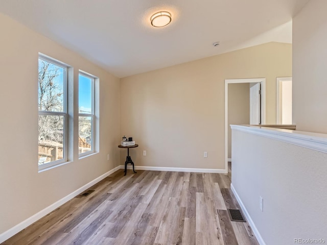 empty room with lofted ceiling and light hardwood / wood-style floors