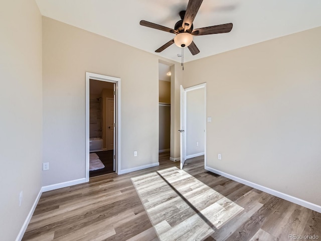 unfurnished bedroom featuring ensuite bath, ceiling fan, light hardwood / wood-style floors, and a closet