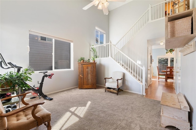 interior space with ceiling fan, light colored carpet, and a high ceiling