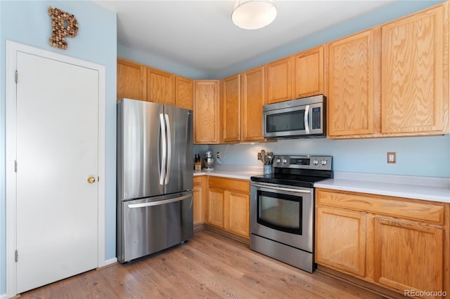 kitchen with appliances with stainless steel finishes, light hardwood / wood-style floors, and light brown cabinetry