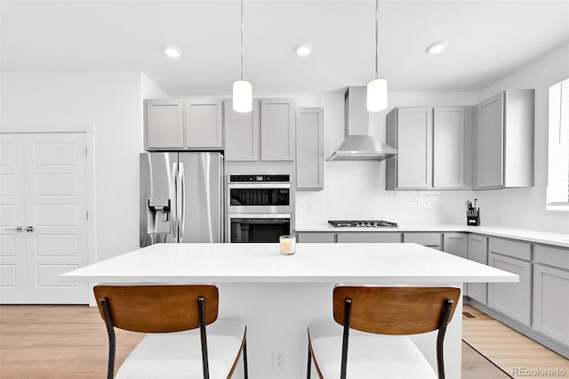 5387 Pierson Ct, Wheat Ridge, CO 80033 - kitchen featuring stainless steel appliances, gray cabinets, wall chimney range hood, a breakfast bar, and backsplash