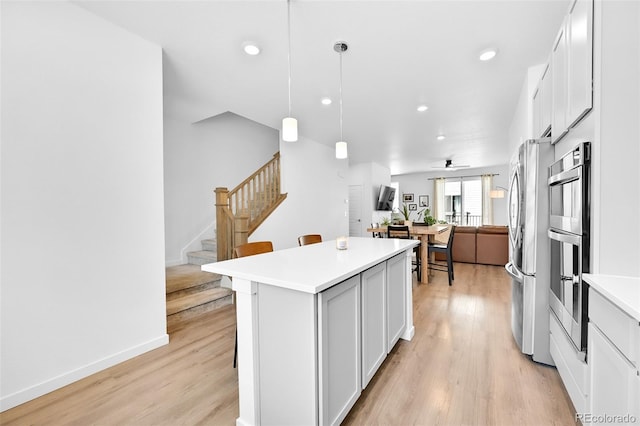 5387 Pierson Ct, Wheat Ridge, CO 80033 - kitchen with stainless steel appliances, a kitchen island, light wood finished floors, recessed lighting, and open floor plan