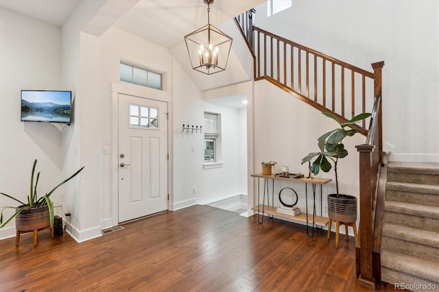 entryway with stairway, hardwood / wood-style flooring, a chandelier, baseboards, and a high ceiling