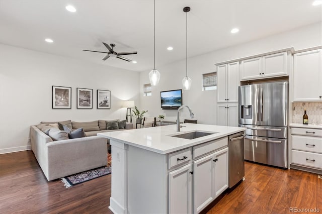 kitchen with stainless steel appliances, a sink, a ceiling fan, light countertops, and decorative backsplash