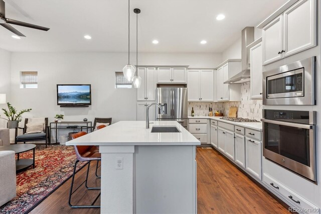 kitchen with stainless steel appliances, a sink, dark wood-style floors, a kitchen breakfast bar, and recessed lighting