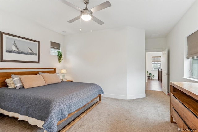 bedroom with multiple windows, light carpet, baseboards, and a ceiling fan