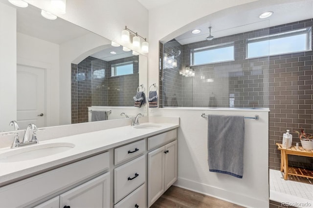 full bath featuring plenty of natural light, a walk in shower, double vanity, wood finished floors, and recessed lighting