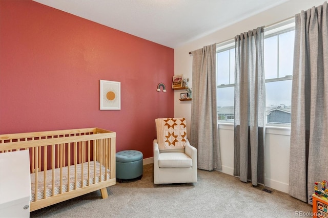 bedroom featuring a crib, carpet flooring, and baseboards