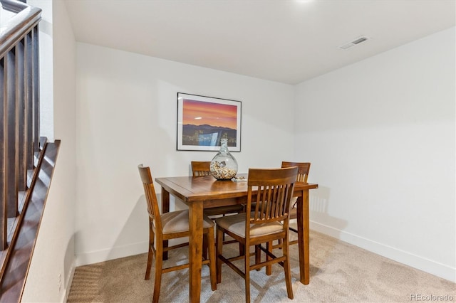 dining room featuring light colored carpet and baseboards