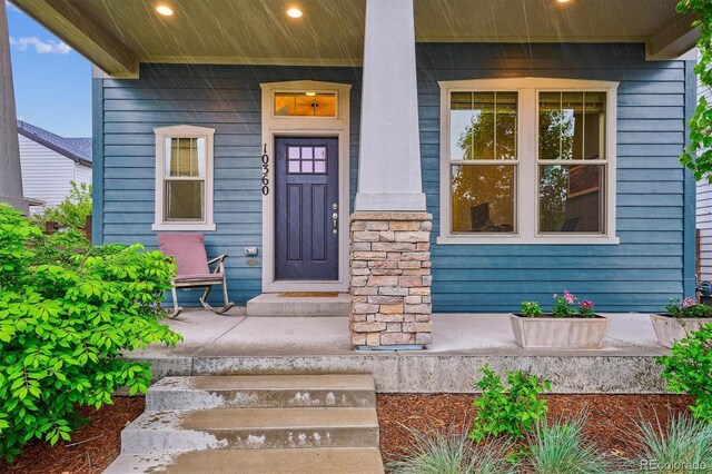 entrance to property with a porch and stone siding