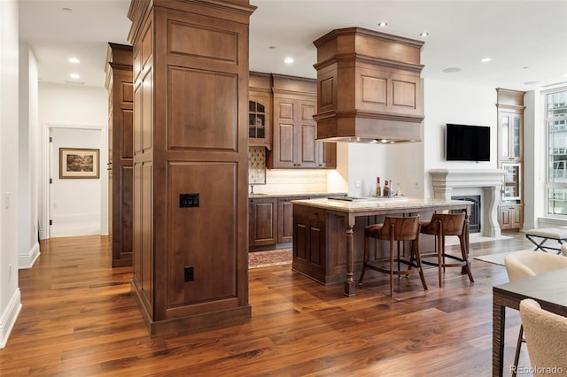 kitchen with backsplash, a center island, dark hardwood / wood-style flooring, and a breakfast bar area