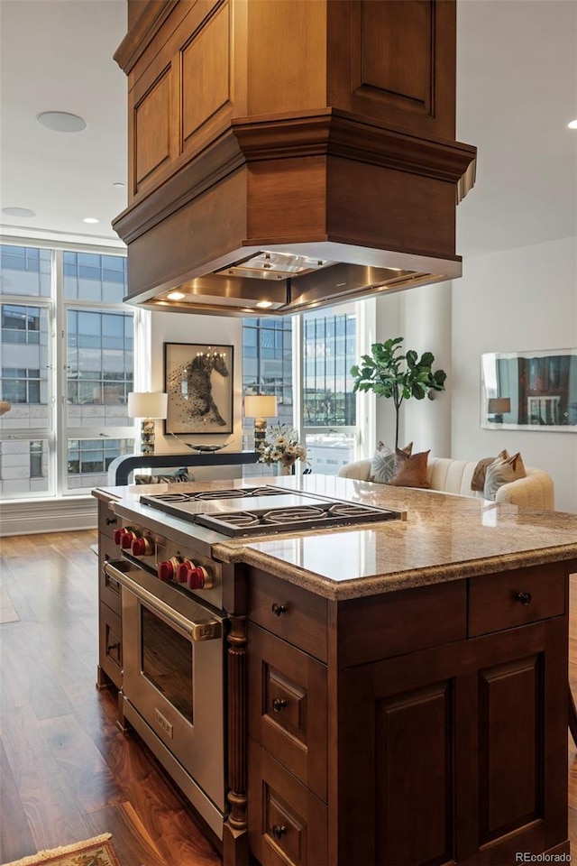 kitchen with premium range hood, light stone counters, luxury stove, and dark hardwood / wood-style floors