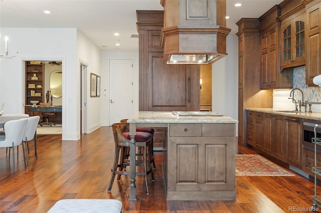 kitchen with light stone countertops, sink, and an island with sink