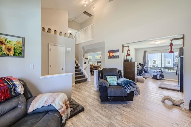 living room with baseboards, stairway, a high ceiling, and wood finished floors