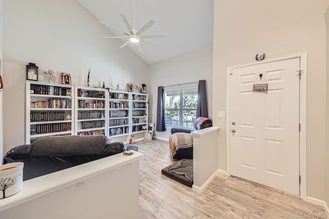 living area with high vaulted ceiling, ceiling fan, light wood-style flooring, and baseboards