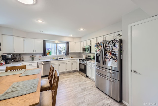 kitchen featuring light wood-type flooring, appliances with stainless steel finishes, white cabinets, and light countertops