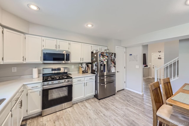 kitchen featuring stainless steel appliances, light countertops, light wood-type flooring, white cabinetry, and recessed lighting