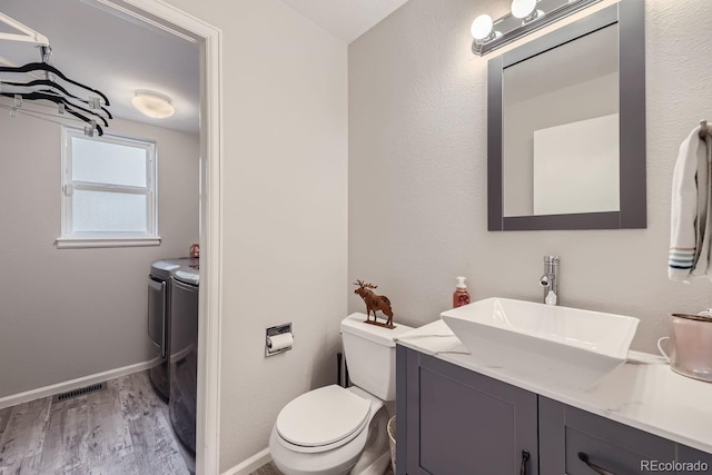 bathroom with wood finished floors, vanity, visible vents, baseboards, and independent washer and dryer