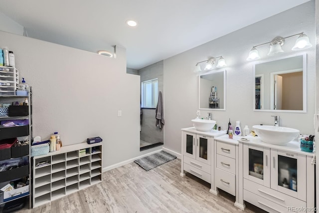 bathroom featuring a walk in shower, a sink, and wood finished floors