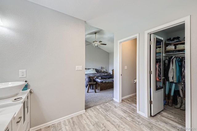 bathroom featuring vaulted ceiling, vanity, baseboards, and wood finished floors