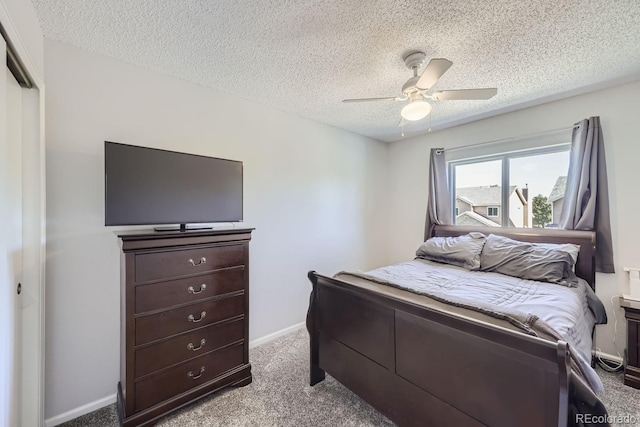 carpeted bedroom with a textured ceiling, a ceiling fan, and baseboards