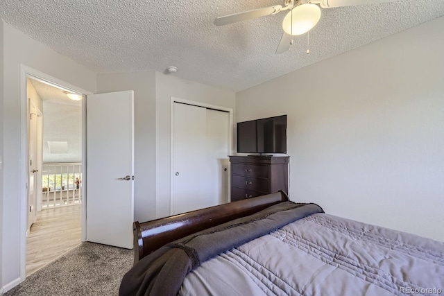 bedroom with carpet floors, a textured ceiling, a ceiling fan, and a closet