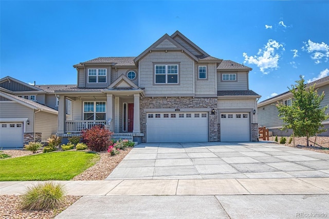 craftsman-style home featuring an attached garage, stone siding, a front lawn, covered porch, and driveway