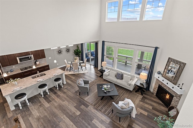 living room featuring a glass covered fireplace, a high ceiling, and dark wood finished floors