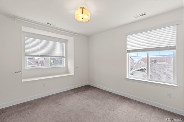 unfurnished room featuring a healthy amount of sunlight, baseboards, and visible vents