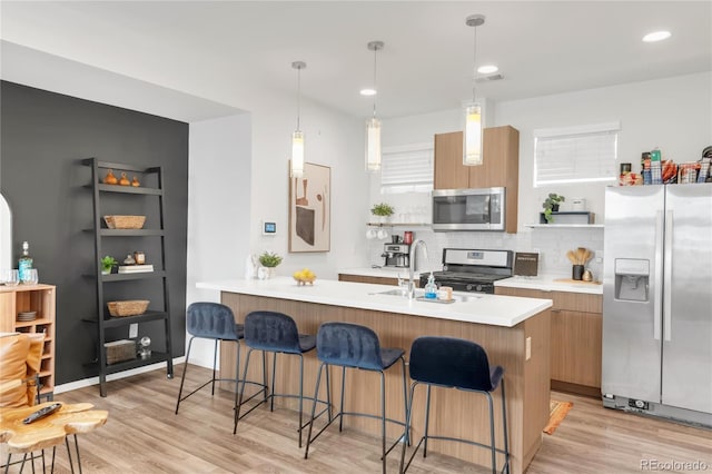1238 Quitman St Unit 2, Denver, CO 80204 - kitchen with appliances with stainless steel finishes, modern cabinets, a breakfast bar area, light wood finished floors, and tasteful backsplash