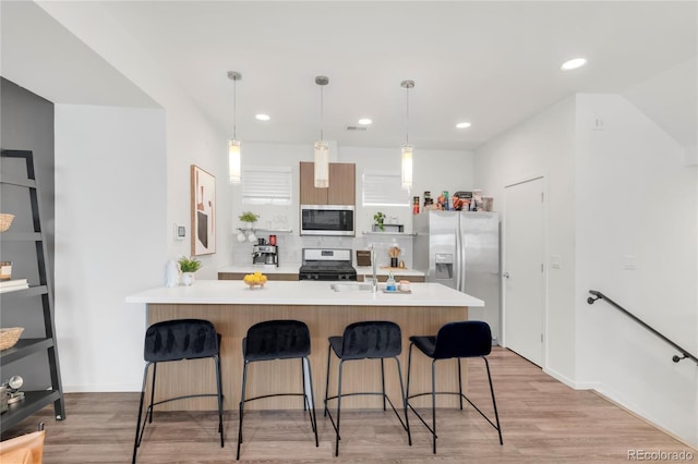 1238 Quitman St Unit 2, Denver, CO 80204 - kitchen featuring appliances with stainless steel finishes, light countertops, a breakfast bar area, tasteful backsplash, and light wood finished floors