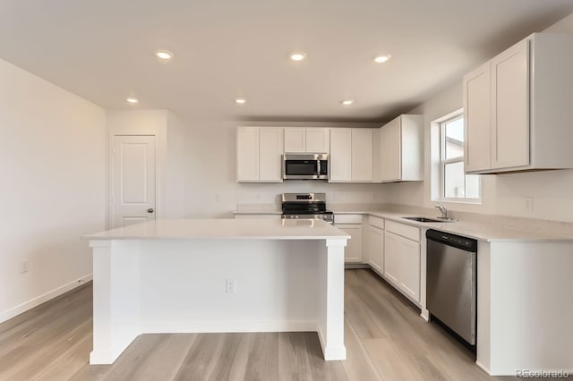 kitchen featuring a sink, light countertops, light wood-style floors, appliances with stainless steel finishes, and a center island