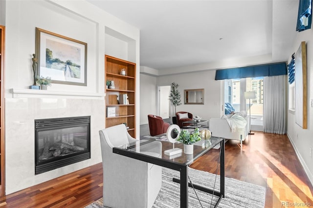 dining area with a tiled fireplace, built in shelves, and dark wood-type flooring