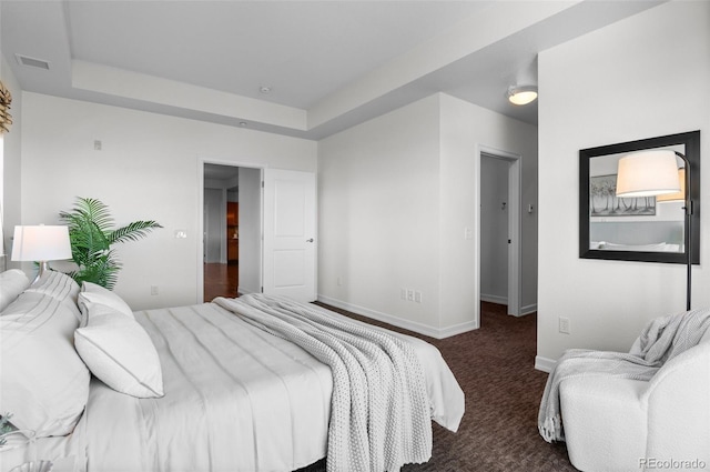 bedroom featuring dark carpet and a tray ceiling