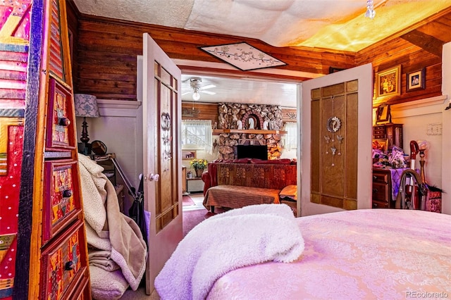 bedroom featuring a fireplace, a textured ceiling, and wood walls