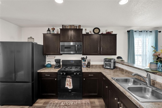 47349 Lily Ave, Bennett, CO 80102 - kitchen with stainless steel appliances, a sink, light wood-type flooring, dark brown cabinetry, and light countertops